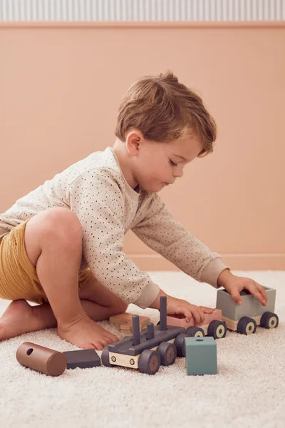 Petit enfant jouant avec un camion en bois : texture, couleur et matière bois Montessori